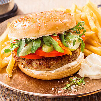 Die Mini-BBQ-Burger sind belegt mit Hackfleisch, Zwiebeln, Gurken, Tomaten, Peperoni und Ruccola. Die Brötchenhälften werden mit Brunch bestrichen. 