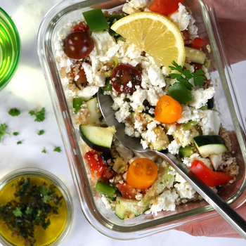 Mediterraner Couscous-Salat in einer Auflaufform, garniert mit knackigem Gemüse wie Zucchini, Feta und Paprika – ein absoluter Genuss!