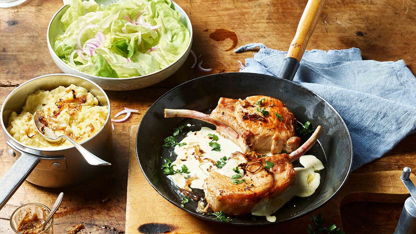 Rezept für Schweinekoteletts mit cremiger Käsesauce und Senf-Kartoffelstampf