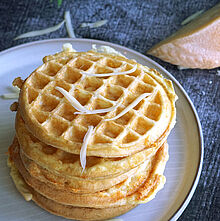 Goldbraun gebackene Keto-Chaffles aus Fol Epi-Käse und Eiern, serviert als Türmchen auf einem Teller. 