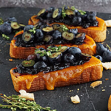 Knuspriges Stullen Rezept mit Cheddar und frischen Heidelbeeren, serviert mit Zitronenthymian auf einer schwarzen Schieferplatte.