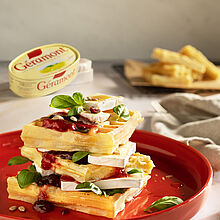 Herzhafte frische Waffeln mit Géramont, Cranberries und Preiselbeeren. Aufgetürmt angerichtet auf einer toten Platte. 