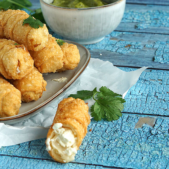 Knusprige Tequeños, golden frittiert und mit cremigem Feta gefüllt, auf einem Teller angerichtet und servierfertig