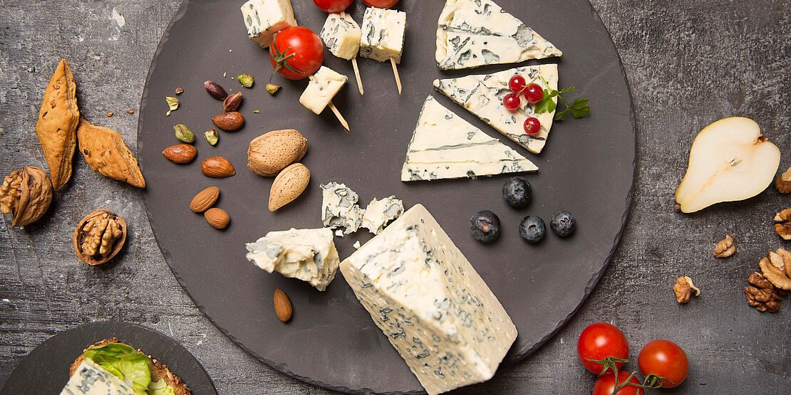 Für genussvolle Käseliebhaber – Steinplatte mit diversen Blauschimmelkäsesorten aus Frankreich. Garniert mit schwarze Oliven.  