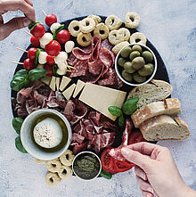 Italienisches Charcuterie Board mit Grana Padano, Parmaschinken, Coppa, Kirschtomaten, Oliven und Basilikumpesto.