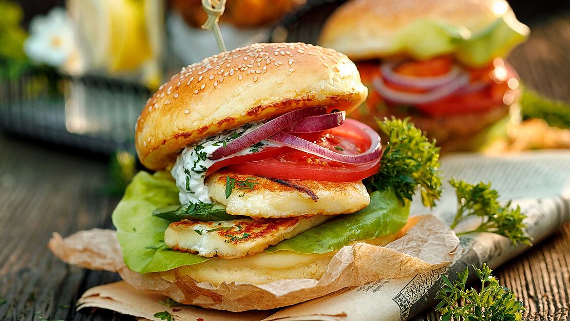 Ausgefallener Halloumi-Burger mit Zwiebeln, Tomaten, Salat und leichtem Dressing.  