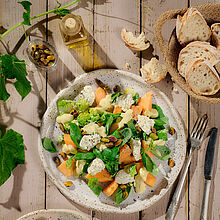 Wunderbarer Sommersalat auf einem runden Teller serviert mit Melone, Basilikum und BRESSO feine Kräuter