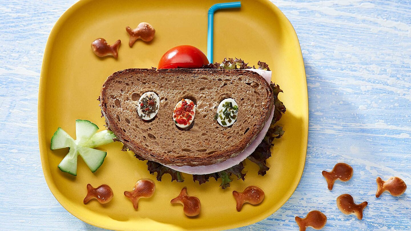 Rezept für ein gesundes Pausenbrot für Kinder und Jugendliche Pfiffiges Pausenbrot als lustiges U-Boot serviert mit Tomate, Gurke und Fischbrezeln