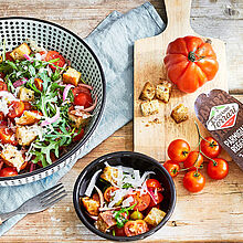 Ein leichter Brotsalat mit Tomaten, Zwiebeln und Oliven, verfeinert mit Parmigiano Reggiano