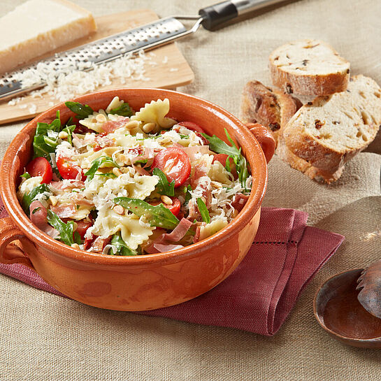 Rustikale Schüssel gefüllt mir italienischen Nudelsalat nach klassischen Rezept. ;it Pesto, Tomaten und Rucola.