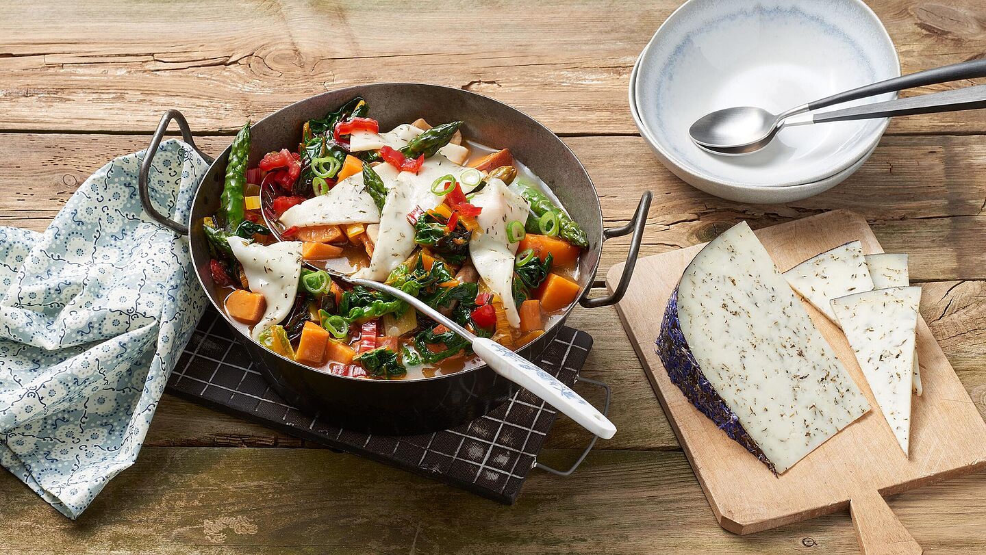 Leckeres einfaches Gemüseragout aus Champignons, Spargel, Mangold und Käse, serviert in einem rustikalen Eisentopf.