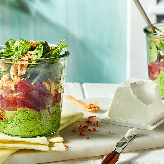 Rote-Bete-Schichtsalat mit Spinatcreme, gerösteten Walnüssen und Röstzwiebeln serviert in einem kleinen Glas