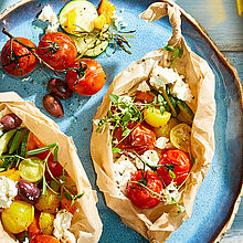 Gewitzte Feta-Päckchen in Backpapier mit mediterranem Gemüse frisch aus dem Ofen 