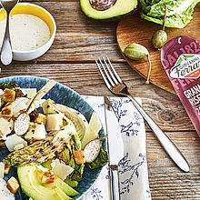 Grana Padano Parmesan als Topping für gegrillten Caesar Salat mit knusprigen Brot Croutons