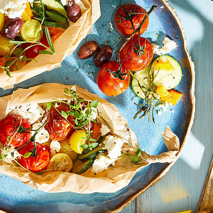 Gewitzte Feta-Päckchen in Backpapier mit mediterranem Gemüse frisch aus dem Ofen 