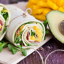 Piadina Avocado-Wrap mit Géramont, Bacon und Mango. Durschgeschnitten und übereinander gelegt.