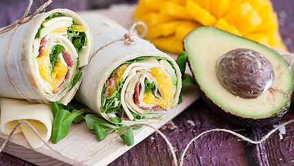 Piadina Avocado-Wrap mit Géramont, Bacon und Mango. Durschgeschnitten und übereinander gelegt.