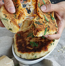 Bolognese, Mozzarella und Knoblauch auf knusprigem Fladenbrot, serviert mit Kräuterbutter und Parmesan.