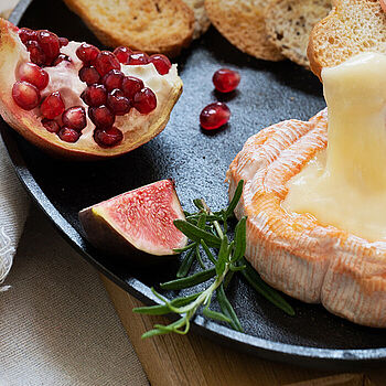 Ofenkäse mit Saint Albray Käse angerichtet mit Feigen, Granatapfel und Baguette. 