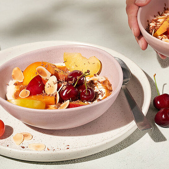 Frische Früchte wie Kirschen, Aprikosen und Äpfel mit cremigem Brunch kombiniert in einer Bowl