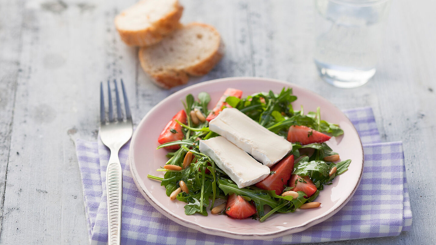 Leichter und farbenfroher Salat aus Rucola, süßen Erdbeeren und knusprigen Pinienkernen, ideal für einfache und gesunde Mahlzeiten