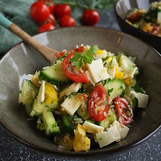 Reissalat Rezept mit gelber Paprika, Kirschtomaten, Gurkenstücken und Fol Epi Classic Käse, serviert in einer grauen Schüssel. 