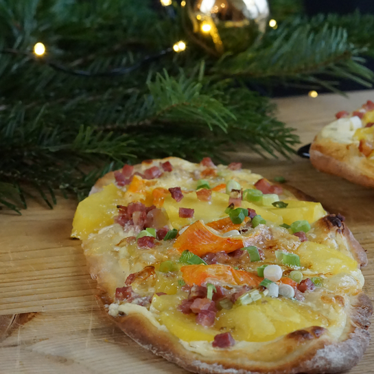 Dinnete mit Kartoffeln, Speck und Saint Albray dekorativ serviert mit einem Tannenbaum Besteck auf einem Holztisch