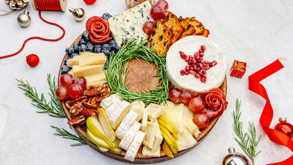 Charcuterie Board Rezept: Ein kunstvoll arrangierter Weihnachtskranz mit Käse, Früchten, Nüssen, Crackern und frischen Rosmarinzweigen als festliche Tischdekoration.