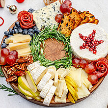 Charcuterie Board Rezept: Ein kunstvoll arrangierter Weihnachtskranz mit Käse, Früchten, Nüssen, Crackern und frischen Rosmarinzweigen als festliche Tischdekoration.