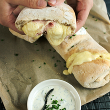 Frisch gebackenes Handbrot wie vom Weihnachtsmarkt, gefüllt mit schmelzendem Raclettekäse und Schinken, serviert mit cremigem Dip.