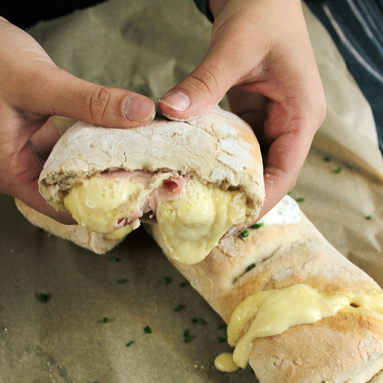 Frisch gebackenes Handbrot wie vom Weihnachtsmarkt, gefüllt mit schmelzendem Raclettekäse und Schinken, serviert mit cremigem Dip.