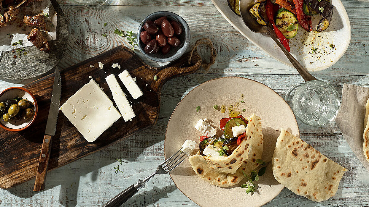 Frisch zubereitete Pita-Taschen gefüllt mit Feta, Grillgemüse, Salat und Oliven, ideal für eine gesunde Mahlzeit.