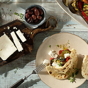 Frisch zubereitete Pita-Taschen gefüllt mit Feta, Grillgemüse, Salat und Oliven, ideal für eine gesunde Mahlzeit.