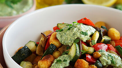 Knuspriger Gnocchi-Salat mit goldbraun gebratenen Kichererbsen, geröstetem Gemüse und cremigem Kräuter-Dip in einer weißen Schüssel.​