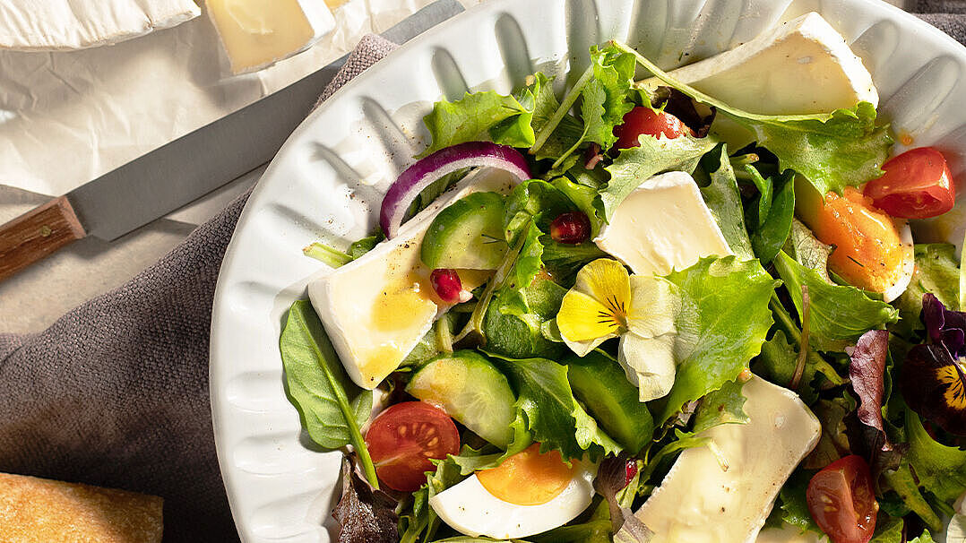 Frühlingssalat in einer weißen Schüssel mit vielen frischen Zutaten wie, Gurken, Zwiebeln, Tomaten und Granatapfelkerne