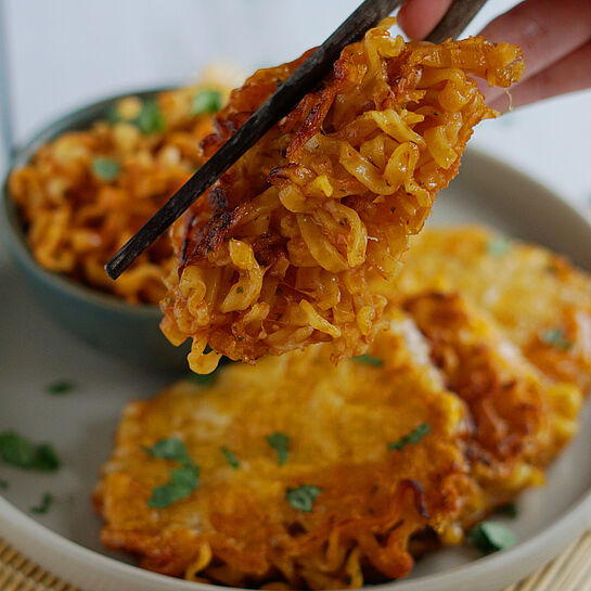 Knusprige Reispapier-Ramen-Wraps mit würzigem Cheddar, aromatischen Ramen-Nudeln in einer Schale serviert.