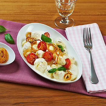 Gnocchi in Käsesoße mit Röstzwiebeln, Cherrytomaten und Kräutern.