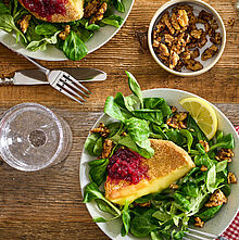 Ein Teller mit knusprigem Back-Camembert, garniert mit Preiselbeeren und frischem Feldsalat