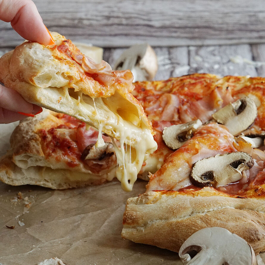 Saftige Pizza voll mit Käse im Boden gefüllt. Dazu leckerer Belag aus Champignons, Kochschinken und noch mehr Käse.  