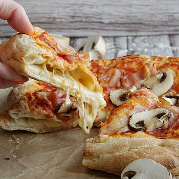 Saftige Pizza voll mit Käse im Boden gefüllt. Dazu leckerer Belag aus Champignons, Kochschinken und noch mehr Käse.  