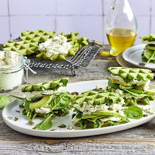 Grüne gefärbte Spinatwaffeln als Mini Sandwich angerichtet mit einer Brunch-Kürbiskerne-Spinatfüllung