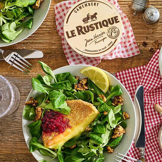 Ein Teller mit knusprigem Back-Camembert, garniert mit Preiselbeeren und frischem Feldsalat