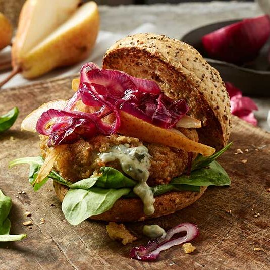 Kerniger Grünkern-Bratling auf einem Burger, verfeinert mit würzigem Saint Agur Blauschimmelkäse