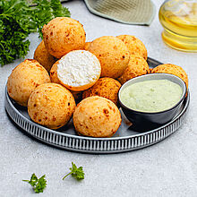 Goldbraune kolumbianische Buñuelos - Feta-Bällchen auf einem Teller, knusprig frittiert und bereit zum Genießen.