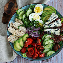 Knackiger Cobb Salat mit frischem Gemüse, knusprigem Bacon, saftiger Hähnchenbrust und cremigem Blauschimmelkäse.