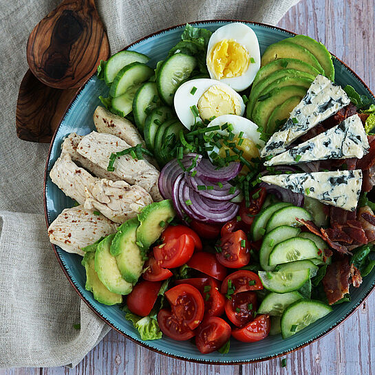 Knackiger Cobb Salat mit frischem Gemüse, knusprigem Bacon, saftiger Hähnchenbrust und cremigem Blauschimmelkäse.