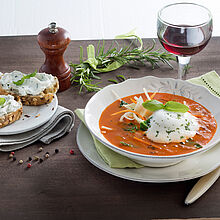 Fein angerichtete selbstgemachte Tomatencremesuppe mit Chavroux Ziegenfrischkäse und frischem Basilikum