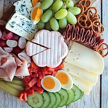 Eine abwechslungsreiche Abendbrot-Platte mit würzigem Käse, frischem Gemüse, herzhaftem Aufschnitt und knusprigem Brot.