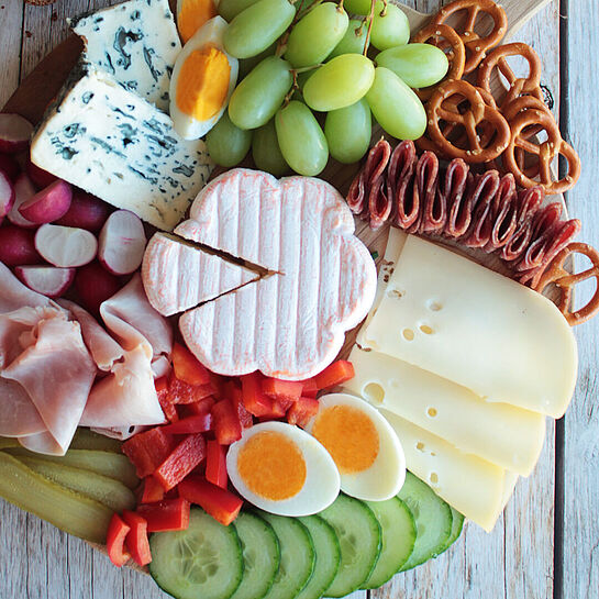 Eine abwechslungsreiche Abendbrot-Platte mit würzigem Käse, frischem Gemüse, herzhaftem Aufschnitt und knusprigem Brot.