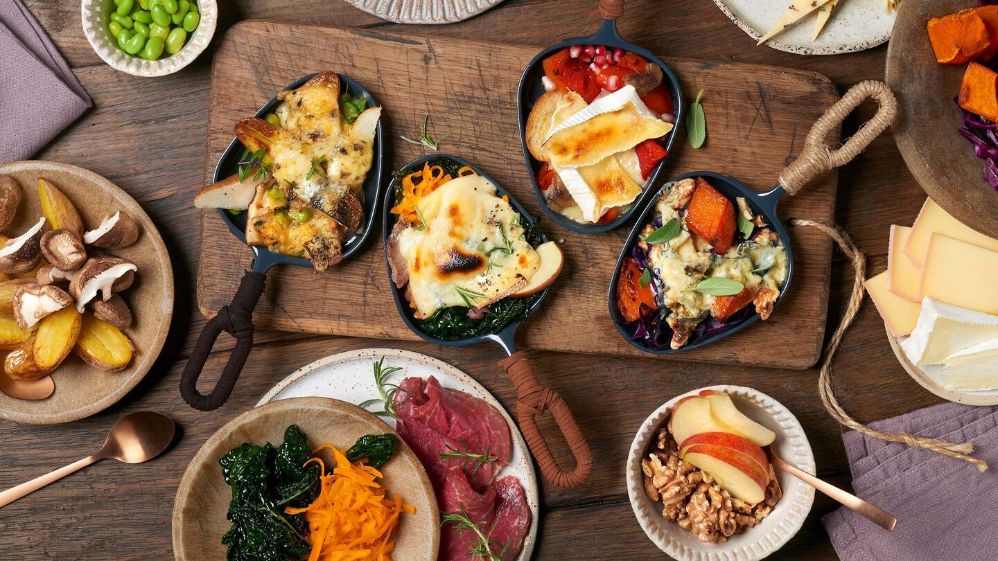 Rustikales Raclette mit vielen Zutaten, wie Obst, Gemüse, Fleisch und Nüssen